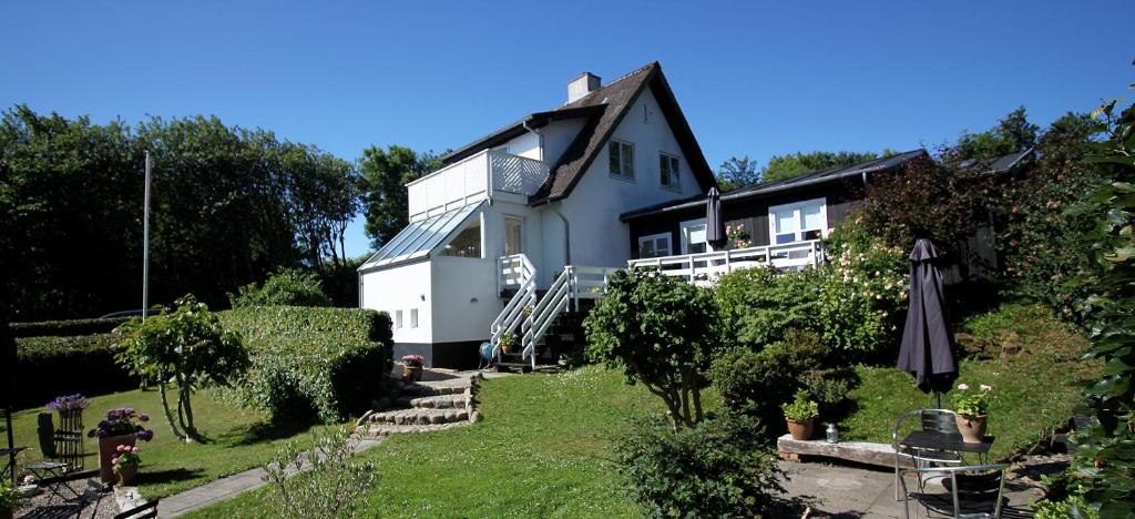 une grande maison blanche avec un parasol dans la cour dans l'établissement Heltoften Bed & Breakfast, à Nykøbing Mors