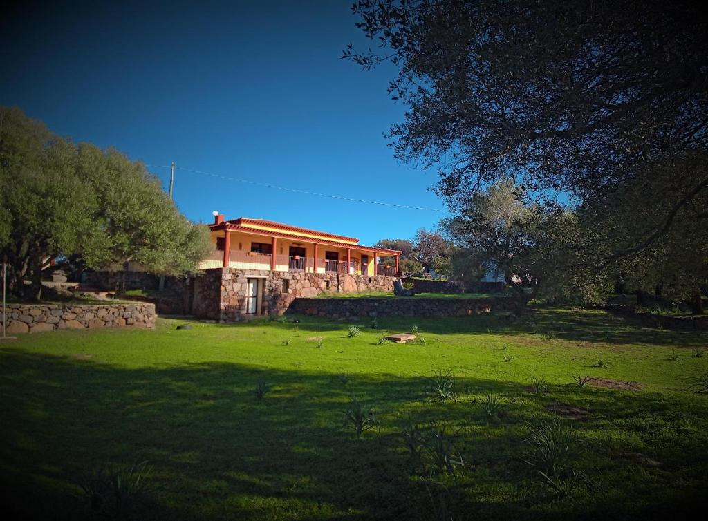 ein Haus auf einem Feld mit einem grünen Hof in der Unterkunft Agriturismo Conca' e Janas in Dorgali