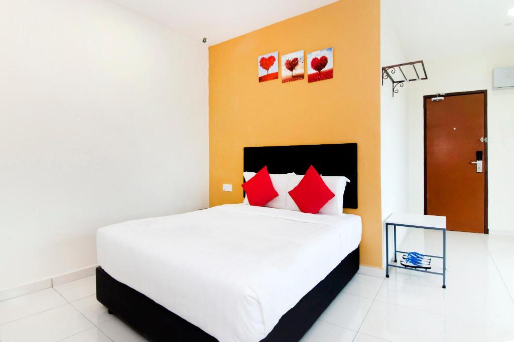 a bedroom with a large white bed with red pillows at Central Hotel in Bahau