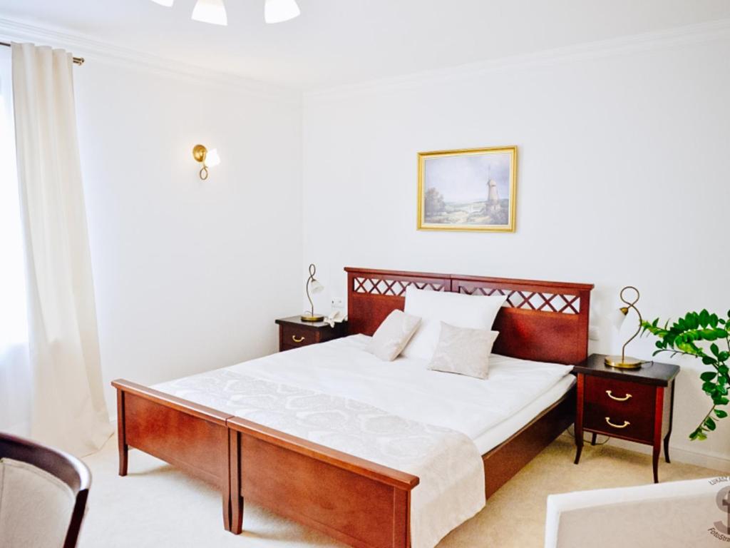 a bedroom with a large bed with white sheets and wooden furniture at Hotel Koloseum in Turek