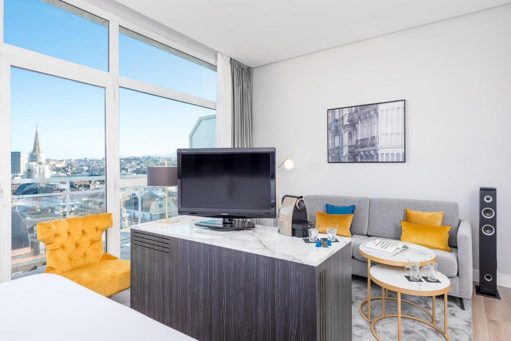 a hotel room with a tv and a couch and a bed at Hotel San Sebastián Orly, Affiliated by Meliá in Donostia-San Sebastián