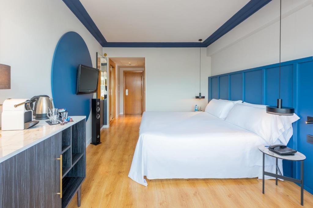 a bedroom with a large white bed and blue walls at Hotel San Sebastián Orly, Affiliated by Meliá in Donostia-San Sebastián