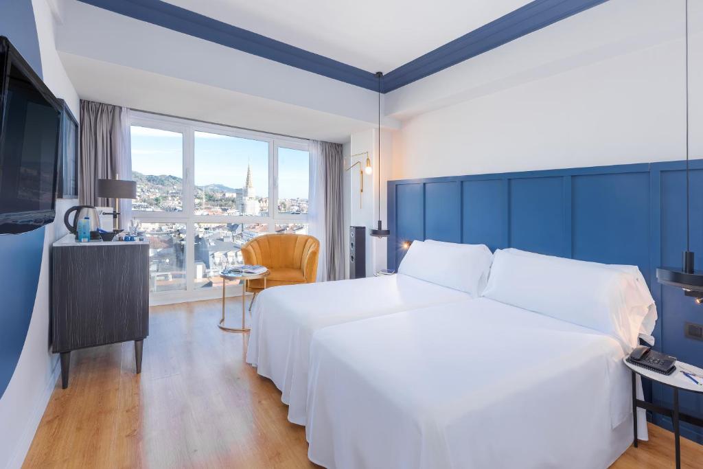 サン・セバスティアンにあるHotel San Sebastián Orly, Affiliated by Meliáの白いベッドと大きな窓が備わるホテルルームです。