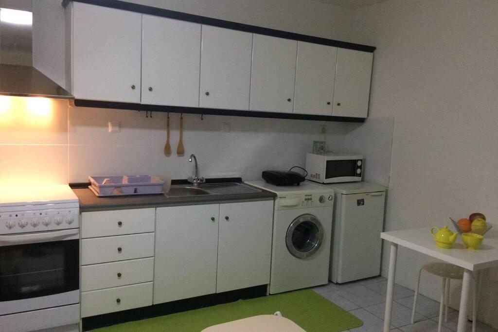 una cucina con armadietti bianchi e lavatrice di Istos Apartment 1 a Salonicco