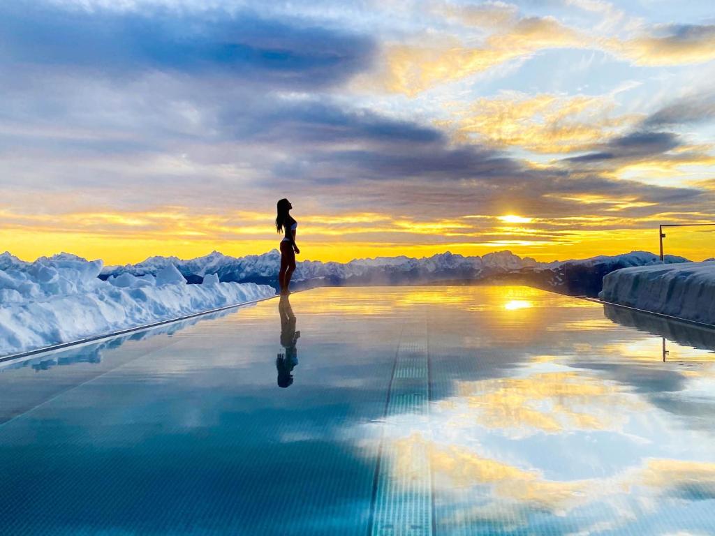 une femme debout au bord d'une piscine dans l'établissement Alpinhotel Pacheiner, à Treffen