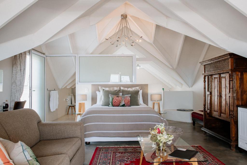 a bedroom with a large bed and a living room at De Linden Boutique Guest House in Paternoster