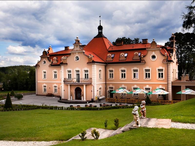 una casa grande con dos personas caminando delante de ella en Hotel Zamek Berchtold, en Strančice