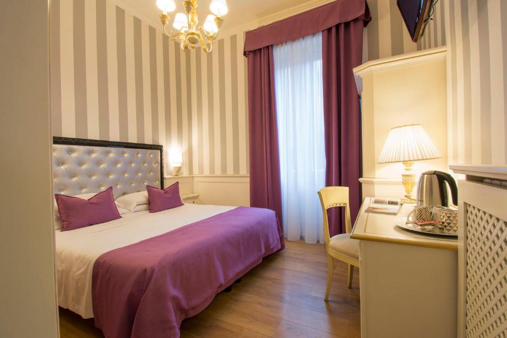Hotel Pedrini في بولونيا: غرفة نوم مع سرير مع ملاءات أرجوانية ومكتب