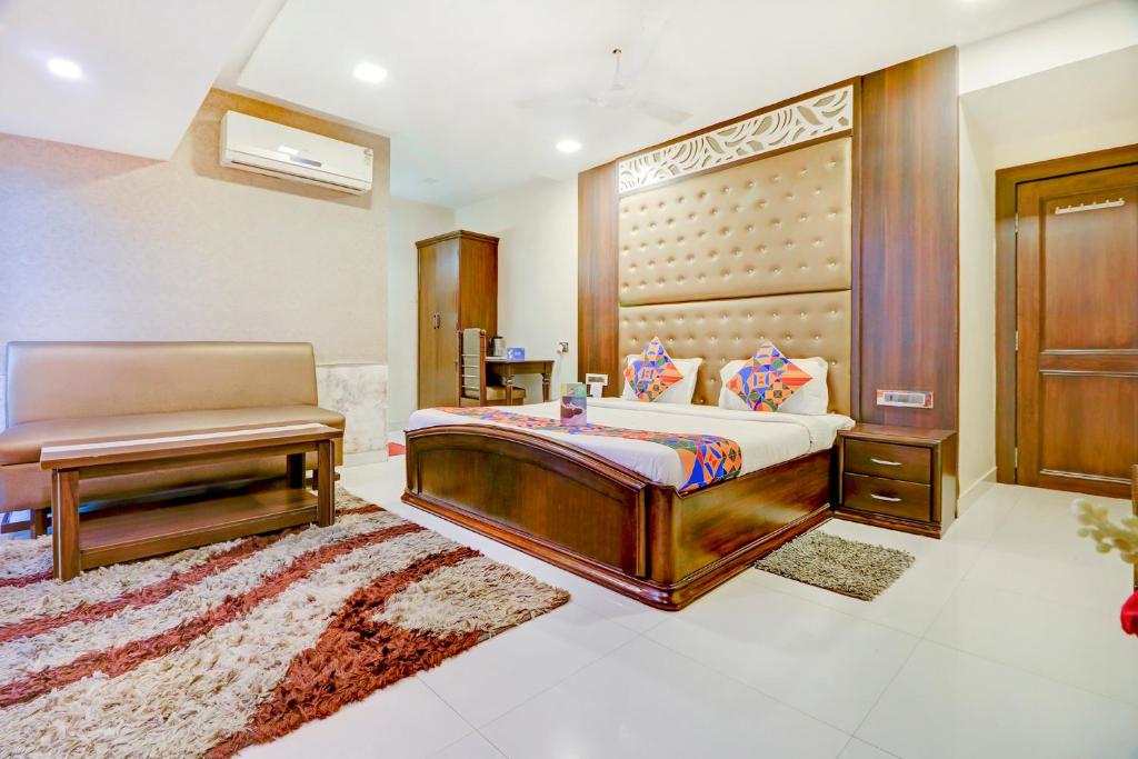 a bedroom with a bed and a bench in it at FabHotel Anandam in Raipur