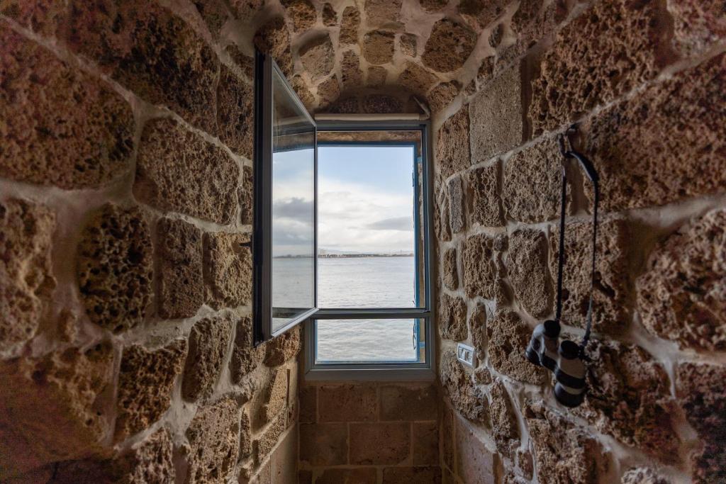 una ventana en una pared de piedra con vistas al océano en Loft in the wall en ‘Akko