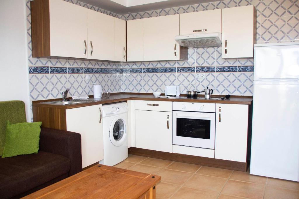 a kitchen with white cabinets and a washing machine at TAO El Cotillo in El Cotillo