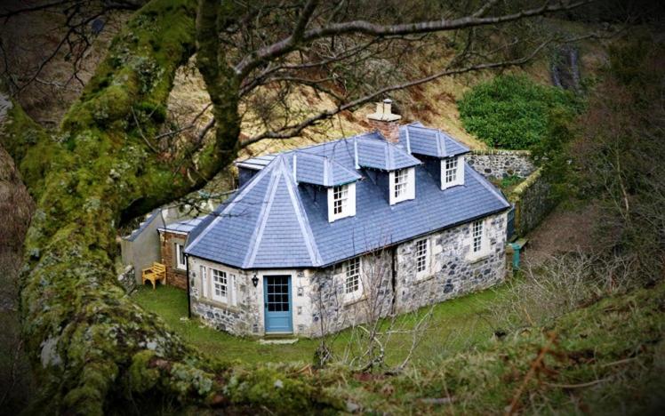 a large house with a blue roof on a hill at Find Me Out Holiday Cottage in Dalmellington