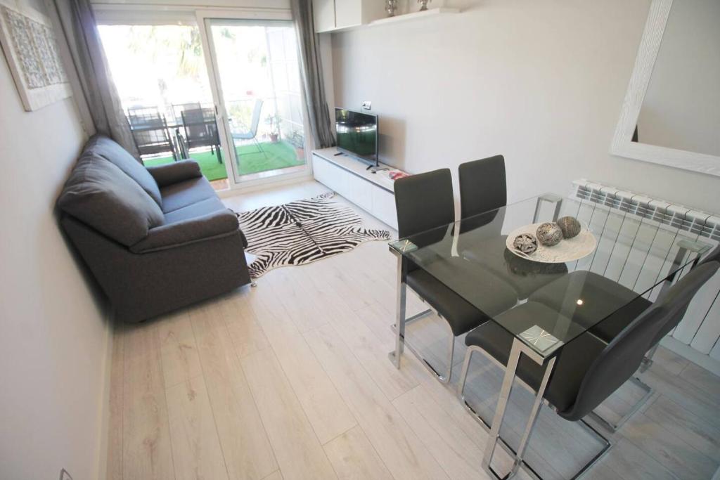 uma sala de estar com uma mesa de vidro e uma cadeira em Family Deluxe Apartment Beach em Castelldefels
