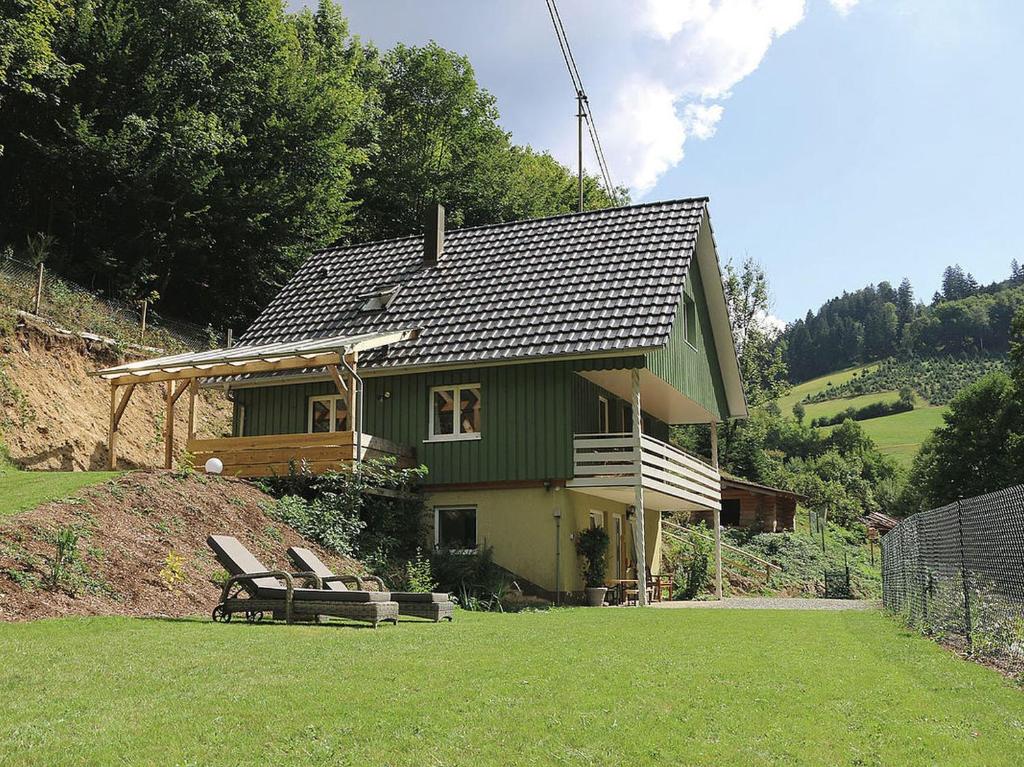 una casa verde con un banco delante en Ferienhaus Froschkönig, en Oberharmersbach