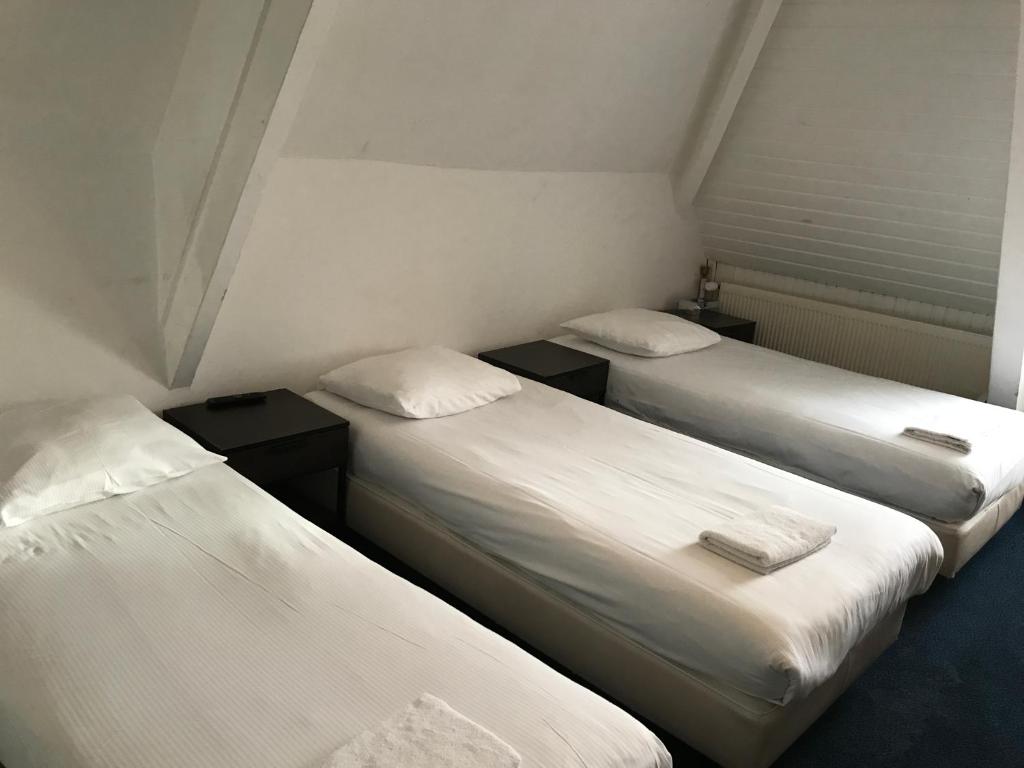 two beds in a small room with white sheets at Budget Hostel Sphinx in Amsterdam