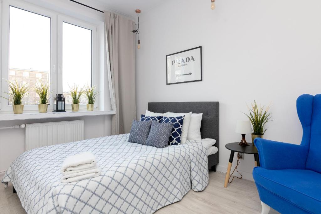 a bedroom with a bed and a blue chair at Stara Ochota Vogue Apartment in Warsaw