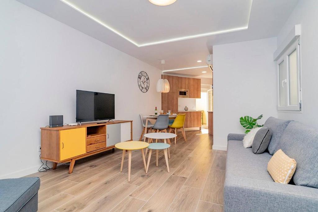 ein Wohnzimmer mit einem blauen Sofa und einem Fernseher in der Unterkunft Bright apartment near Casa de Campo by Batuecas in Madrid