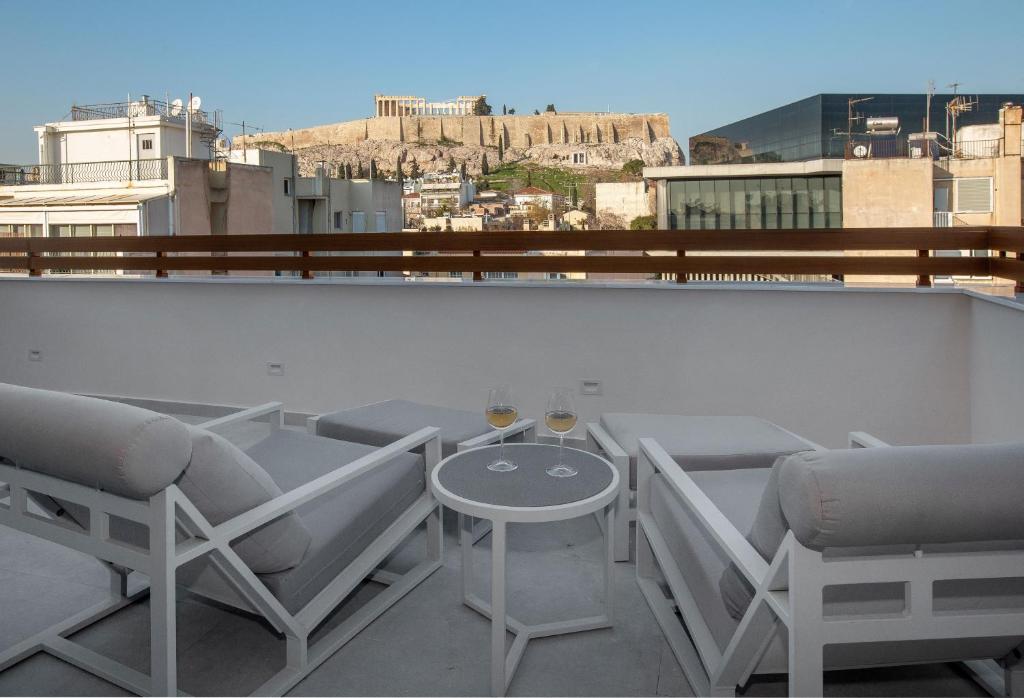 uma varanda com cadeiras e uma mesa com copos de vinho em Acropolis Golden Suites by GHH em Atenas