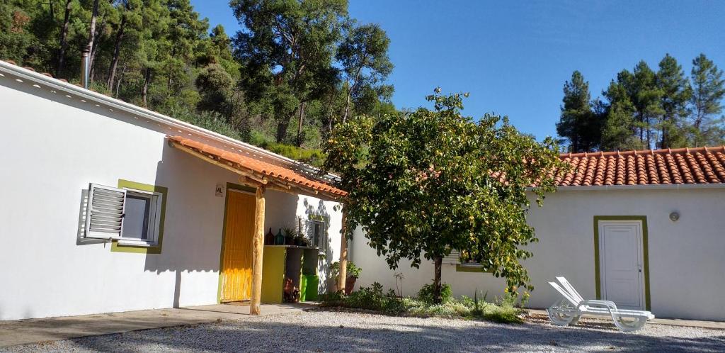 a white house with a chair next to a tree at Quinta da Barroquinha in Vale de Prazeres
