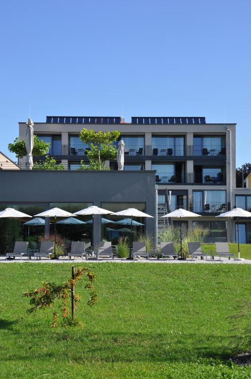 a building with tables and umbrellas in front of it at Hotel Traube am See in Friedrichshafen