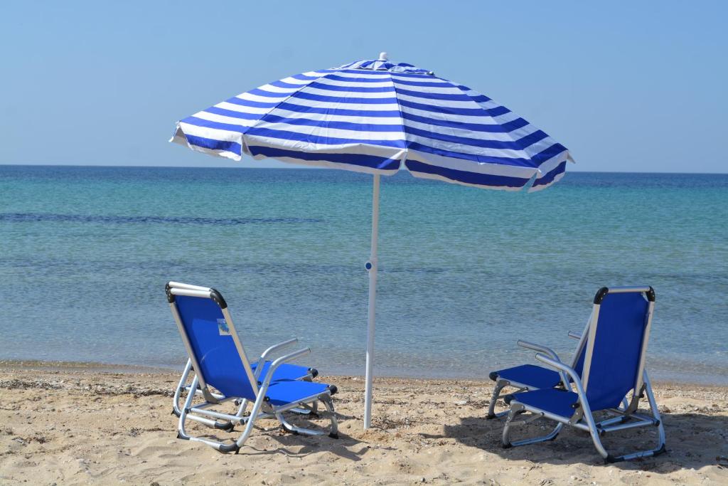 twee stoelen en een parasol op het strand bij Zoi Apartments in Paralia Dionysiou