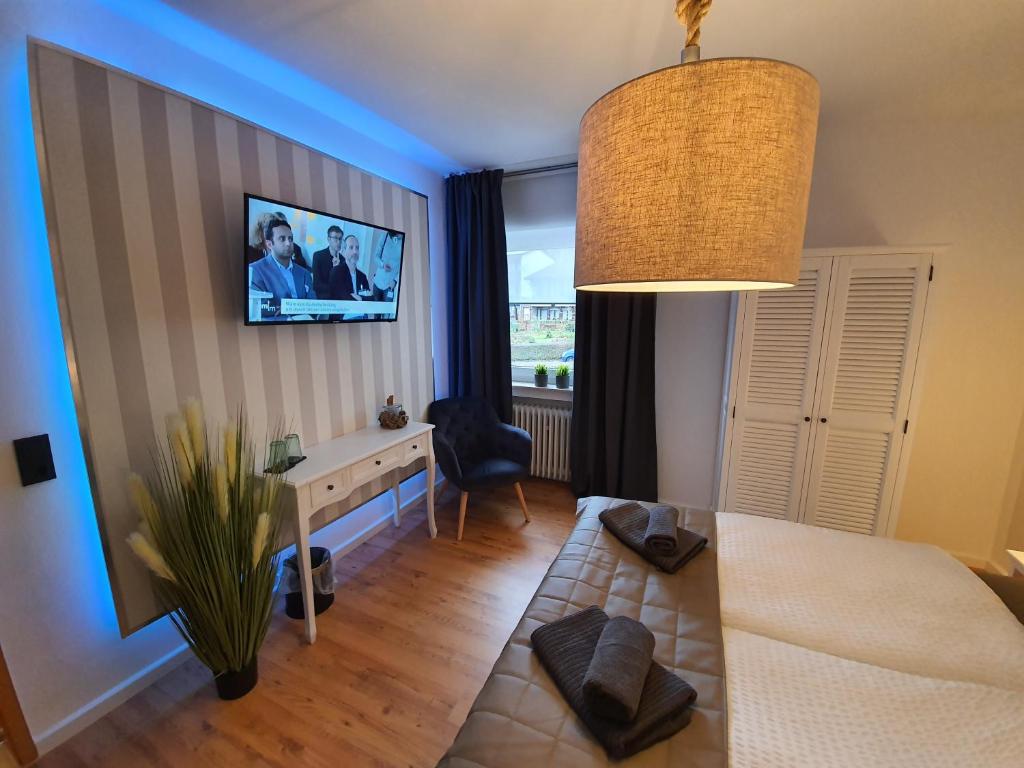 1 dormitorio con cama, escritorio y TV en la pared en Reinhardshäusle Pension & Wellness, en Reinhardshausen