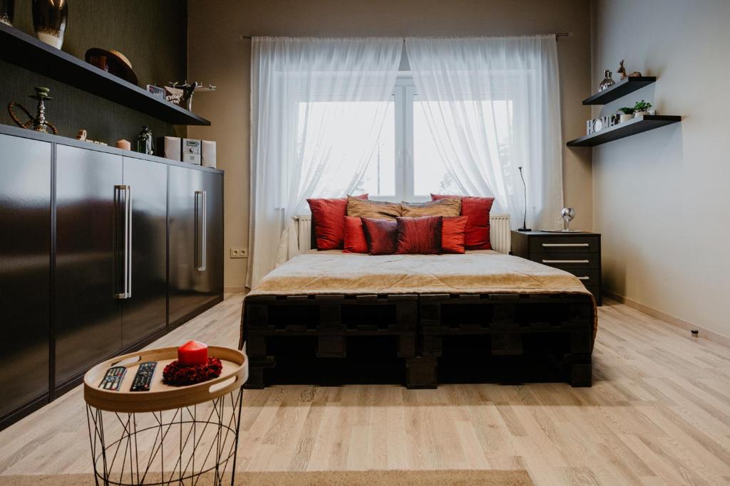 ジェールにあるKényelmes apartman a belváros szélénのベッドルーム1室(赤い枕のベッド1台、窓付)
