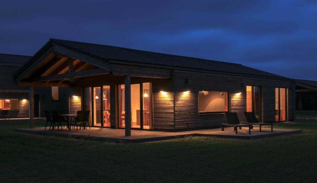 a small cabin with a porch at night at Gud Jard Lodge Nr 13 - Design-Ferienhaus mit exklusiver Ausstattung in Pellworm