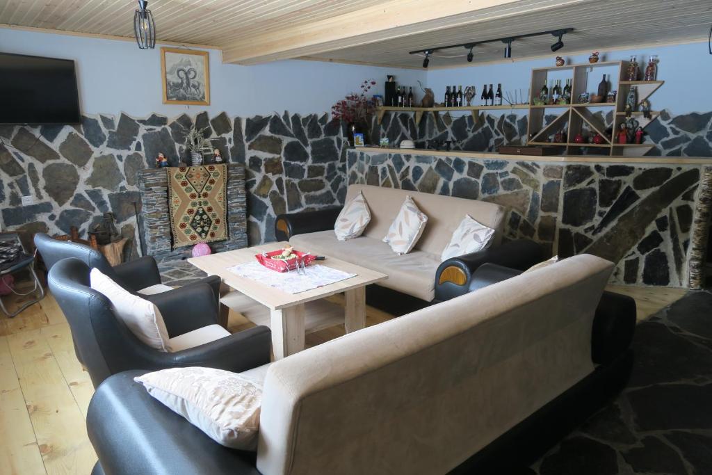 sala de estar con sofás, mesa y pared de piedra en Guest House Lashmina en Mestia