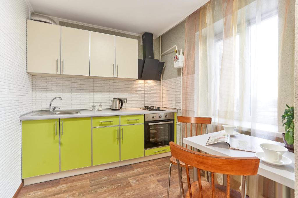 una cucina con armadi verdi e un tavolo con sedie di "Domino" 4 Apartments a Charkiv