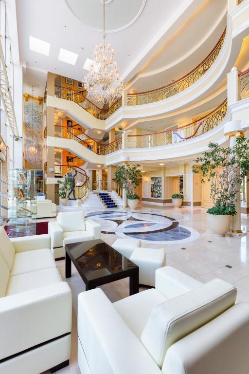 a lobby with white furniture and a chandelier at Hotel Mazurkas in Ożarów Mazowiecki
