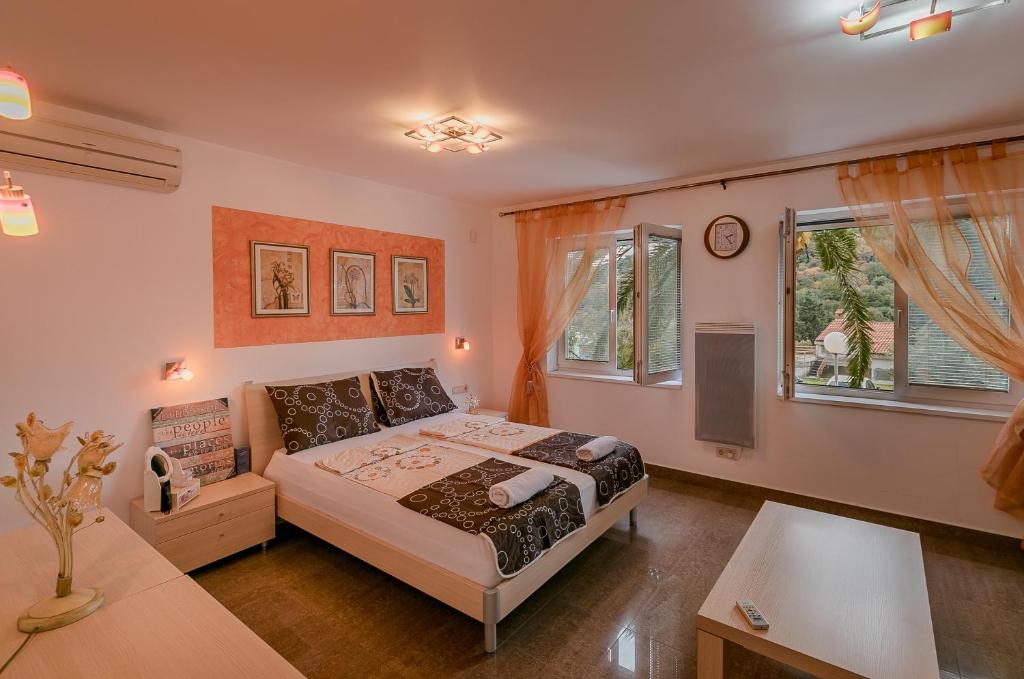 ein Schlafzimmer mit einem Bett und zwei Fenstern in der Unterkunft Palm Point Apartment in Petrovac na Moru