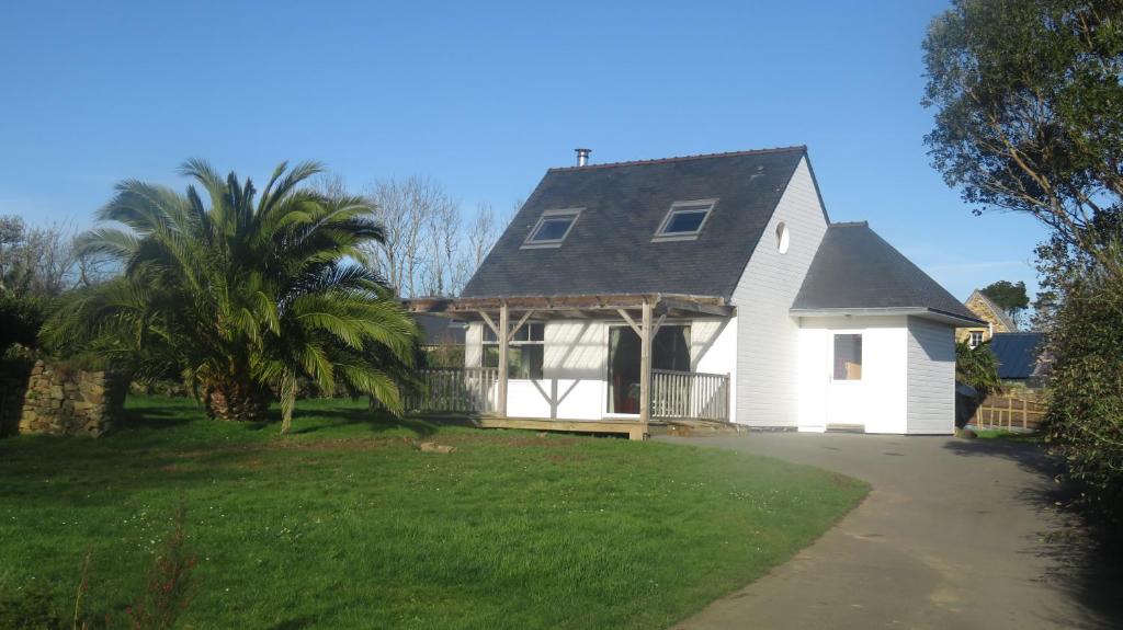 ein weißes Haus mit einer Palme im Hof in der Unterkunft LE PETIT COIN DE PARADIS in Roscanvel