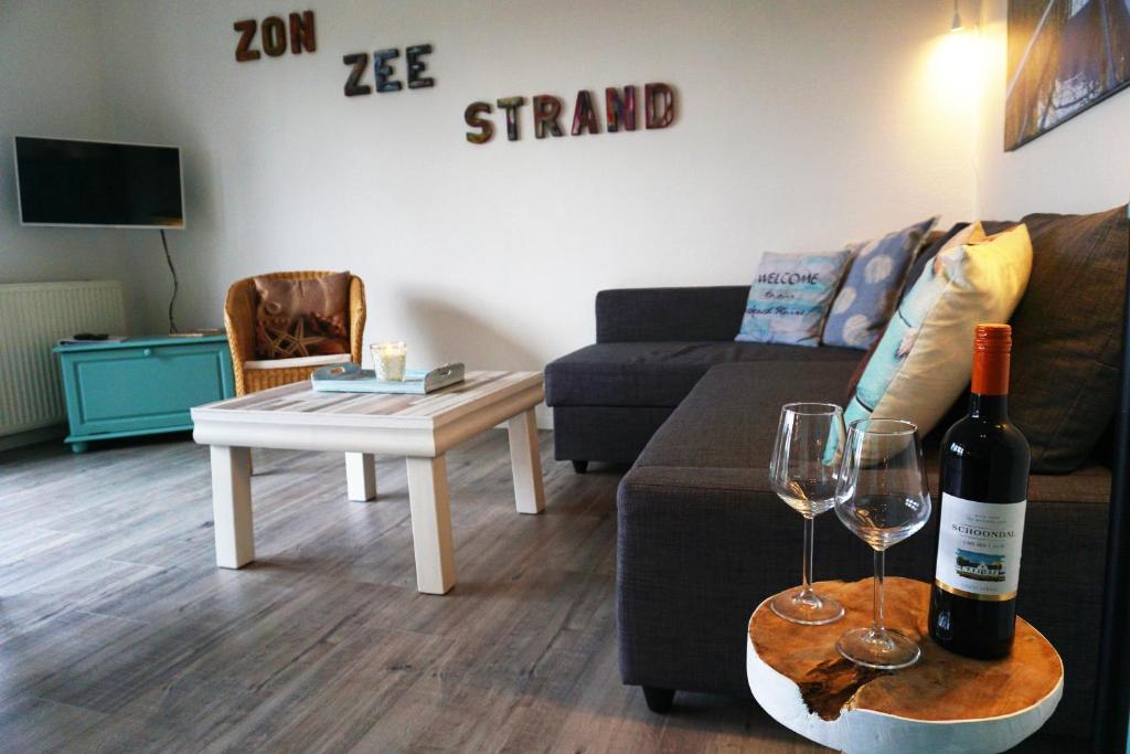 a living room with a bottle of wine and two glasses at Strandslag Juliana 135 in Julianadorp