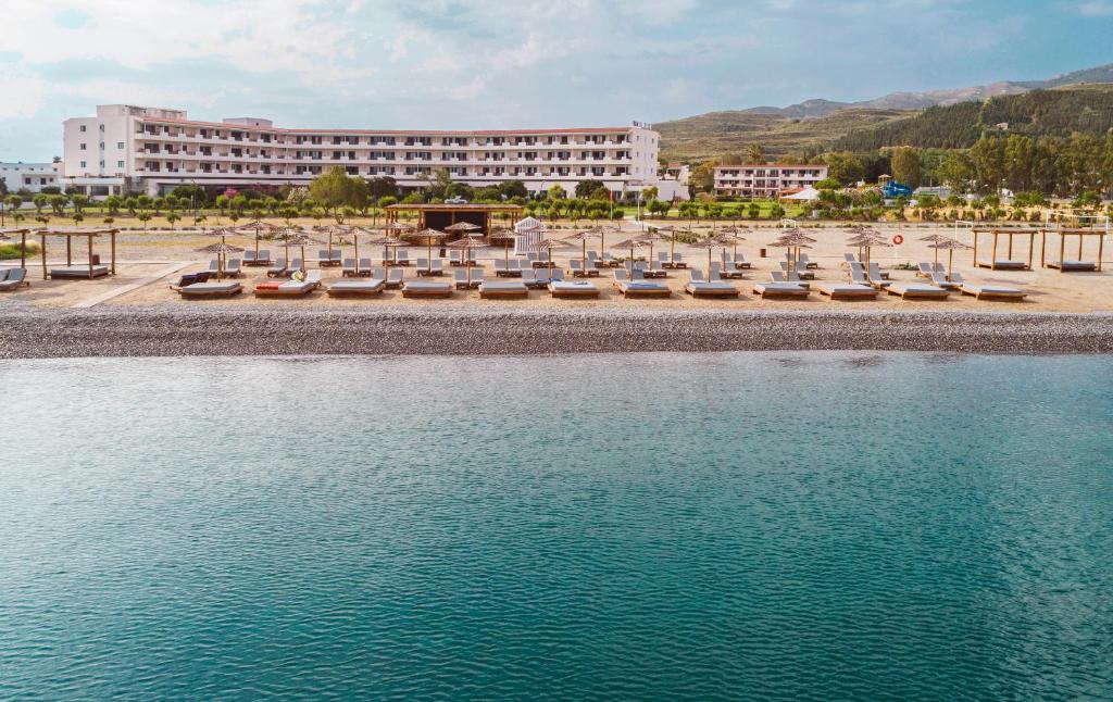 un hôtel avec une rangée de chaises et une masse d'eau dans l'établissement Mitsis Ramira, à Kos