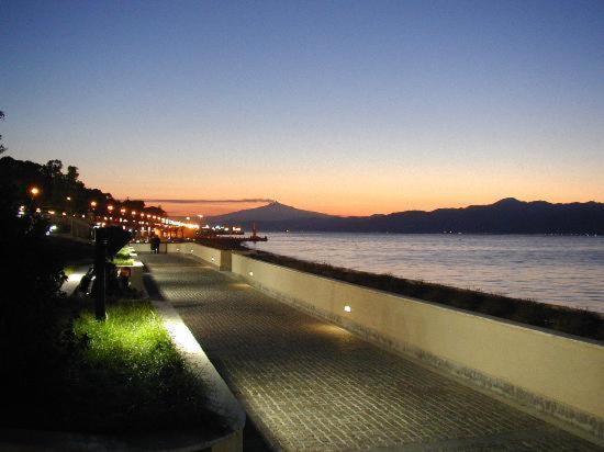 a walkway next to a body of water at night at Vista Mare Rooms in Reggio Calabria