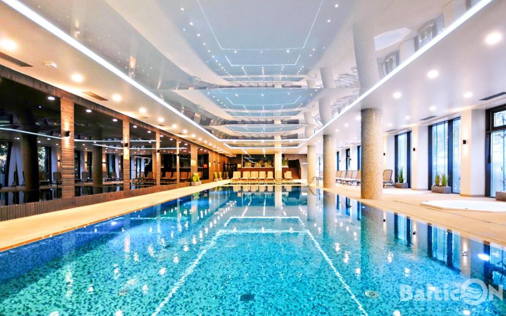 a large swimming pool with blue water in a building at Apartamenty BalticON Nadmorskie Tarasy in Kołobrzeg