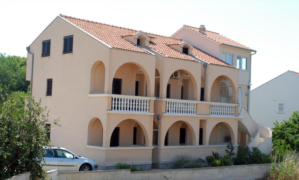 a large house with a balcony and a car at Apartments Mediterranean Sundance in Vodice