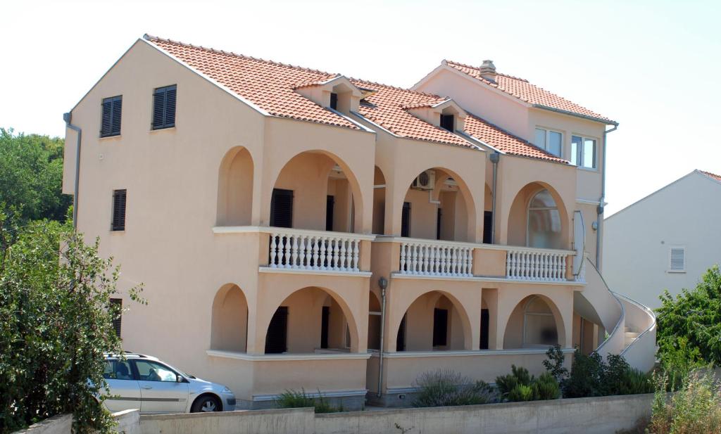 una grande casa con balcone e una macchina di Apartments Mediterranean Sundance a Vodice