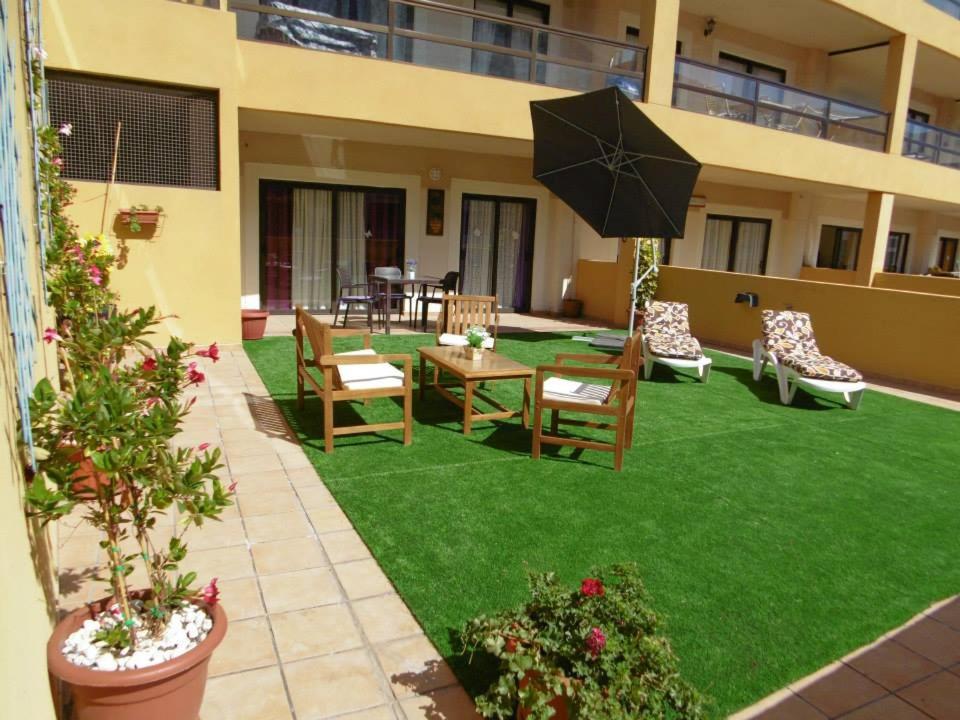 a lawn with chairs and a table and an umbrella at 330 - Edf Aguamarina - Vacation Rental Home in the coast line of Golf del Sur in San Miguel de Abona