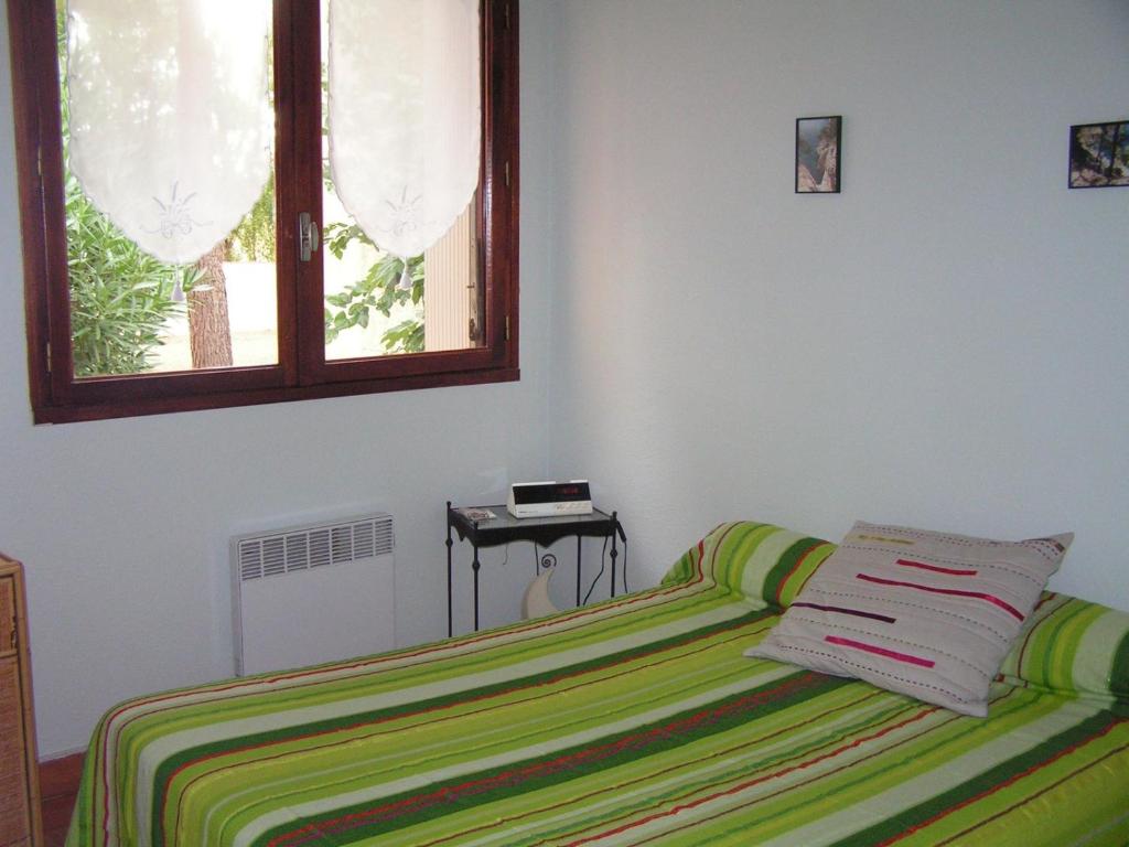 a bedroom with a bed with a green and yellow blanket at valras appartement T2 proche mer et port in Valras-Plage