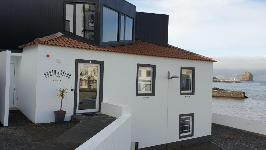 ein weißes Gebäude mit schwarzen Fenstern und Wasser in der Unterkunft Porto Velho Boutique Hostel in Madalena