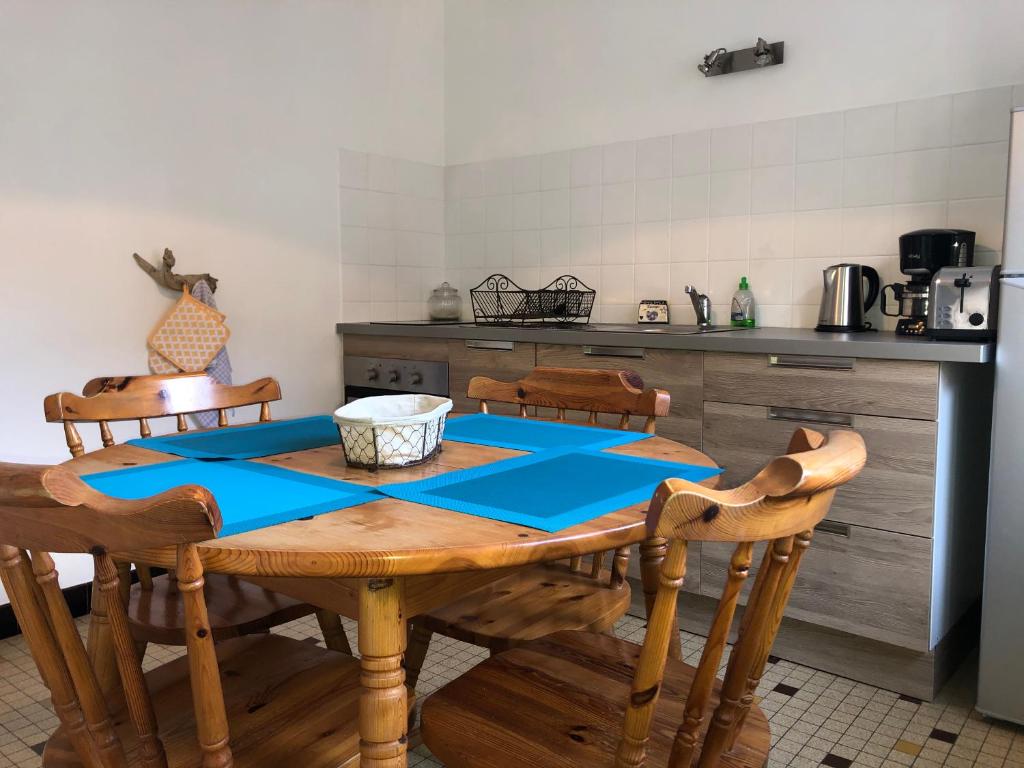 a kitchen with a wooden table and wooden chairs at Villa Coquelicot Plage in Le Tréport