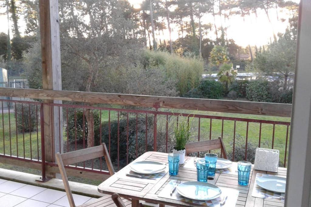 - une table et des chaises en bois sur une terrasse couverte dans l'établissement T2 Mabouya Ondres plage avec piscine et tennis, à Ondres