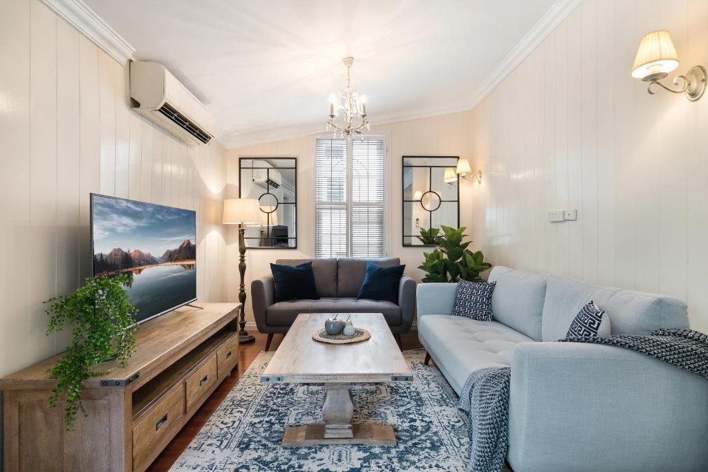 a living room with a blue couch and a tv at Contemporary Cottage in Perfect Lifestyle Address in Brisbane