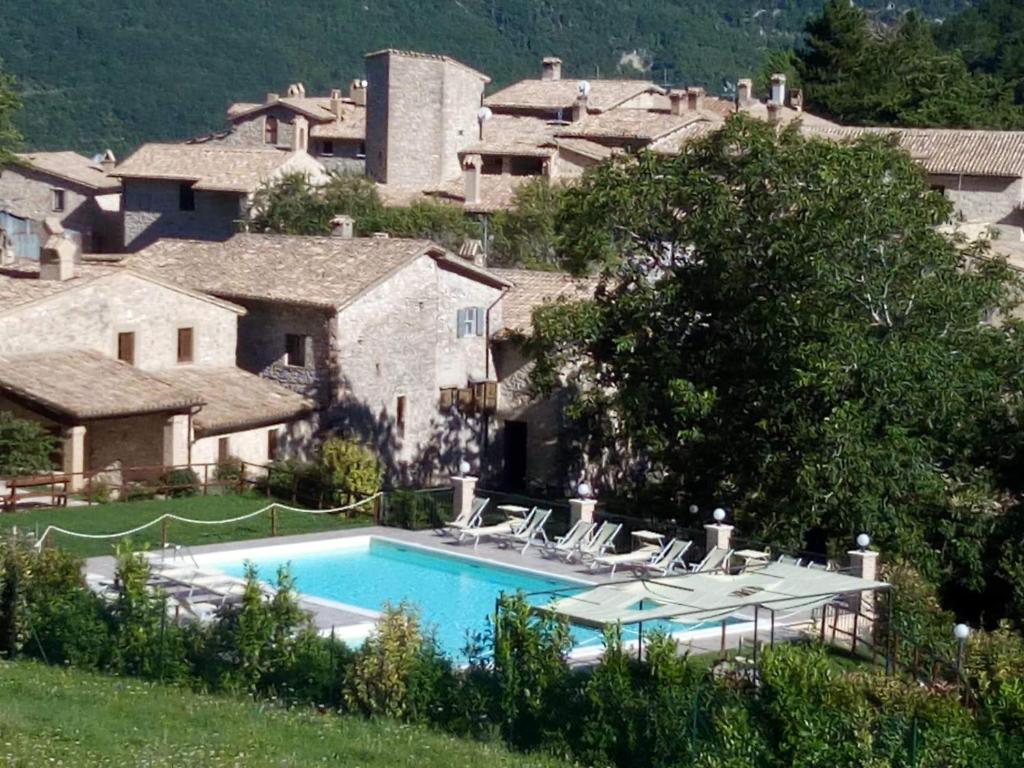 una piscina frente a una casa con montaña en Castello di Acera, en Campello sul Clitunno