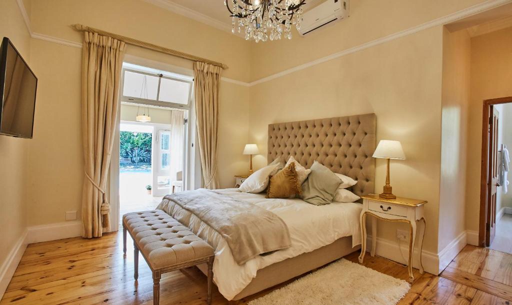 Un dormitorio con una cama grande y una lámpara de araña. en Villa Puccini, en Ciudad del Cabo