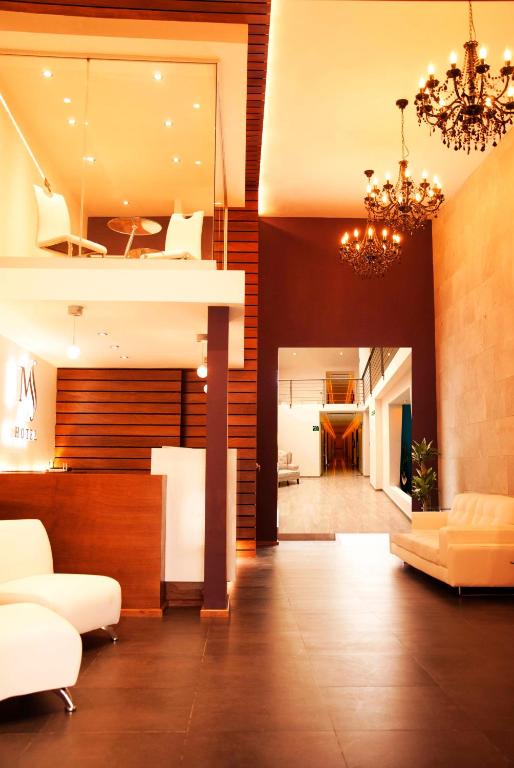 Una sala de estar con muebles blancos y una lámpara de araña. en Hotel MS, en Cholula