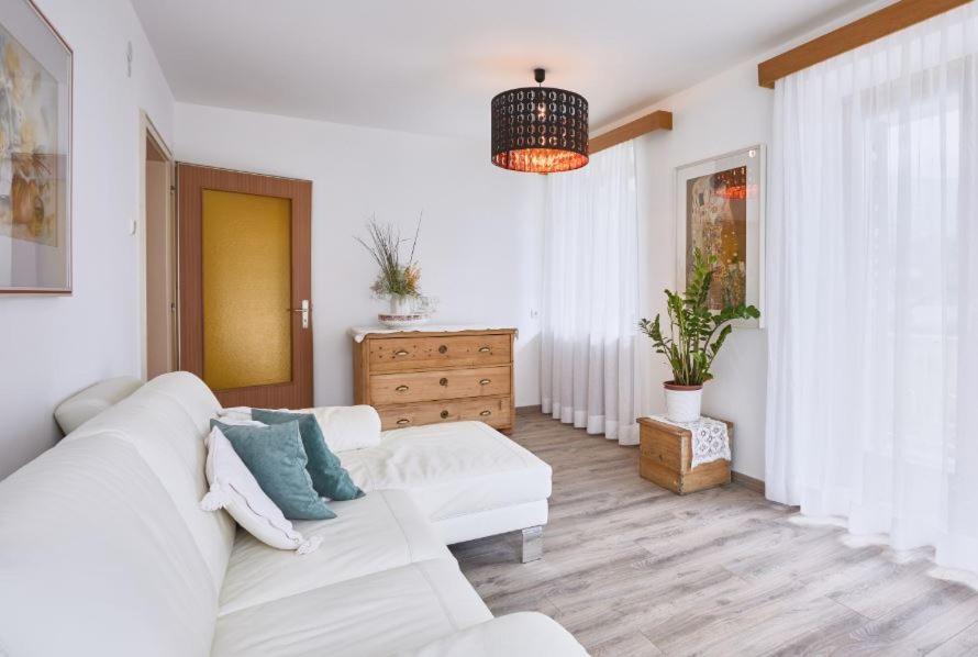 Sala de estar blanca con sofá blanco y cómoda en Apartmenthaus Haringer, en Novacella