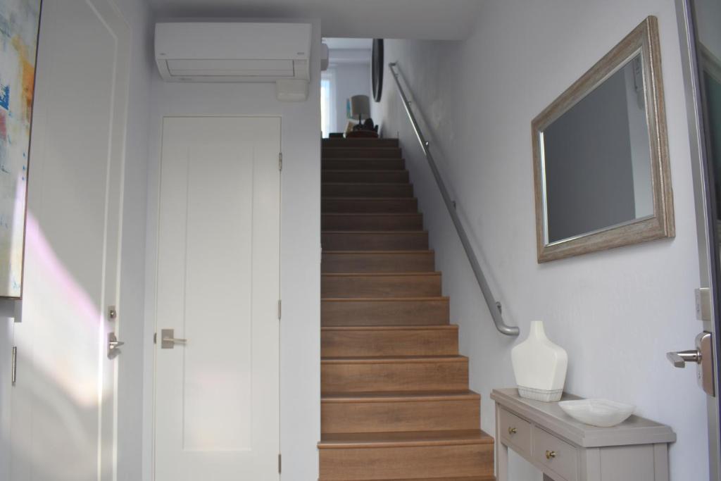 una escalera en una casa con paredes blancas y suelo de madera en 245 San Miguel en Avila Beach
